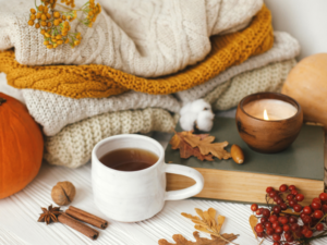 photo of sweaters with candle and tea and fall leaves