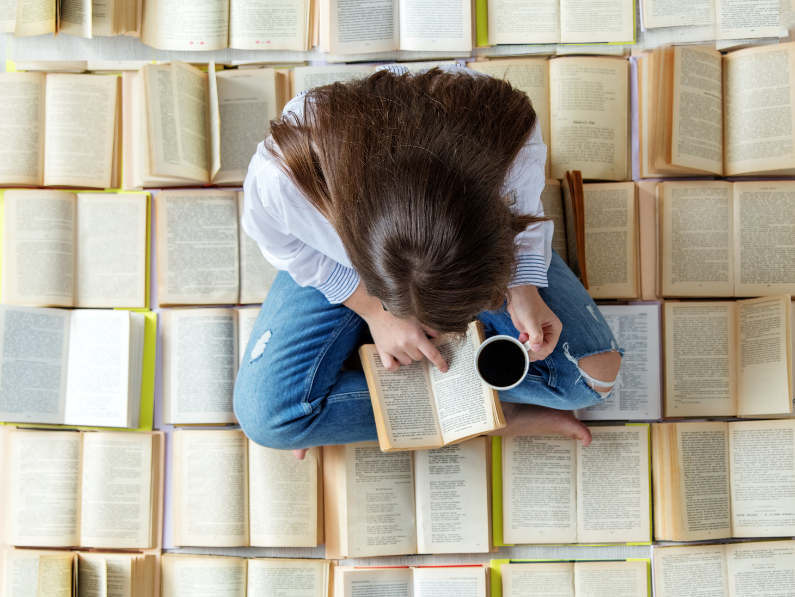 photo of woman reading a book while sitting on multiple books learning how to read on a budget