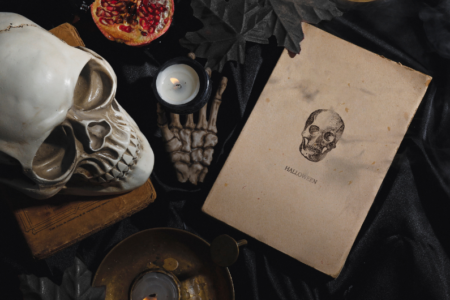 photo of spooky detritus with skeleton, pomegranate and aged paper that says halloween