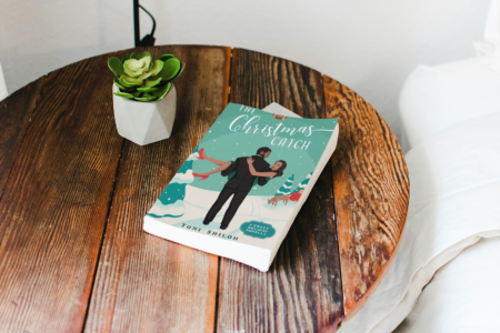 photo of book the christmas catch by Toni Shiloh sitting on a table near a bed