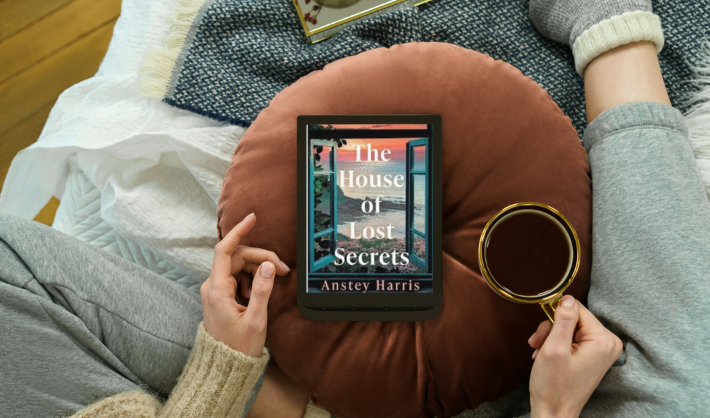 photo of woman sitting on couch with coffee and e-reader with photo of book the house of lost secrets by Anstey harris