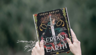 photo of woman holding book servant of earth by Sarah Hawley above trees outside