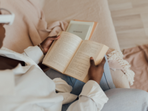 photo of black woman sitting on her couch and reading