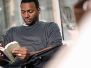 photo of black man reading a book in a public space