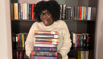 photo of kathleen haagenson standing in front of bookshelves holding 2025 March TBR